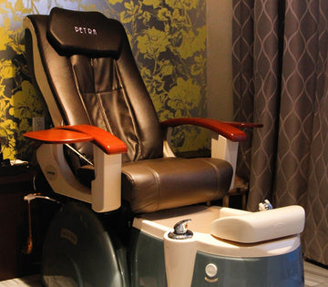 Luxurious spa pedicure chair with brown leather seat, wooden armrests, and a foot basin.