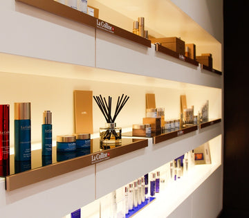 Luxurious skincare products displayed on illuminated shelves. Includes La Colline jars, bottles, and reed diffusers, creating an elegant and serene ambiance.